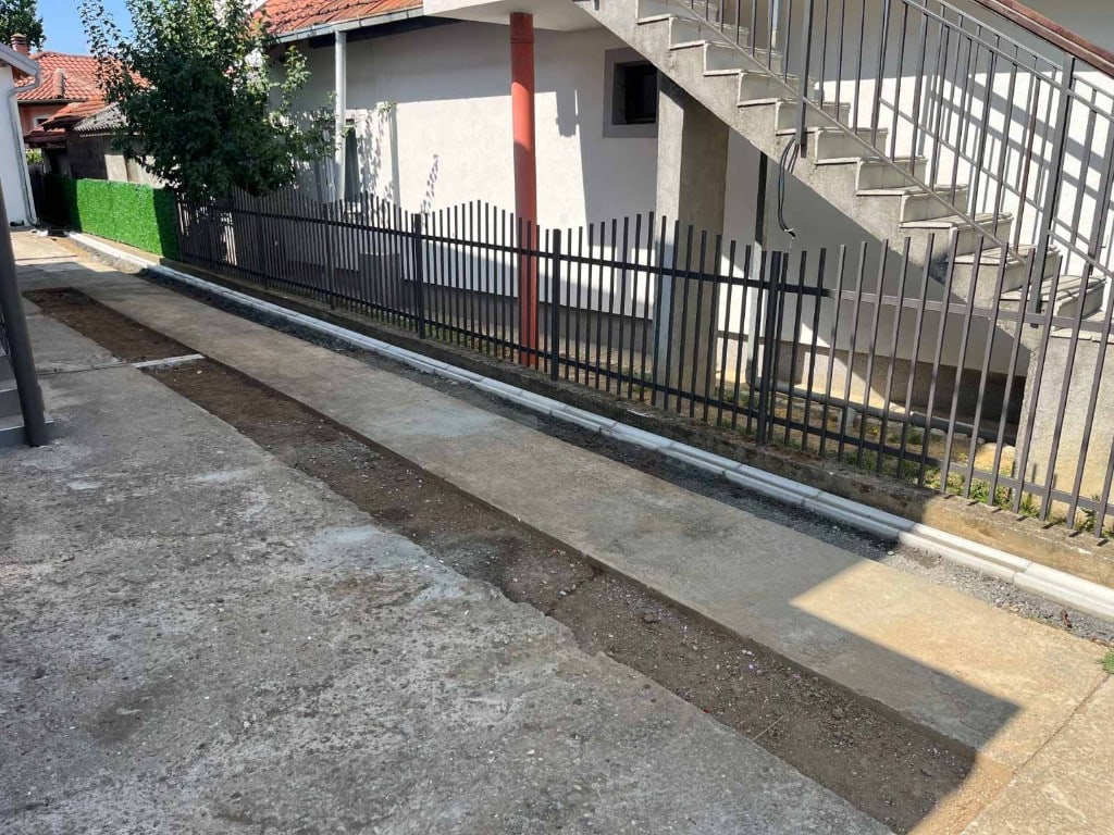 Pripremni radovi za asfaltiranje sa postavljenim betonskim ivičnjacima pored ograde